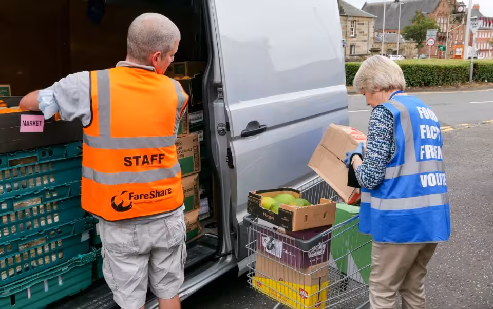 Man hands food out of a van for a food bank volunteer.